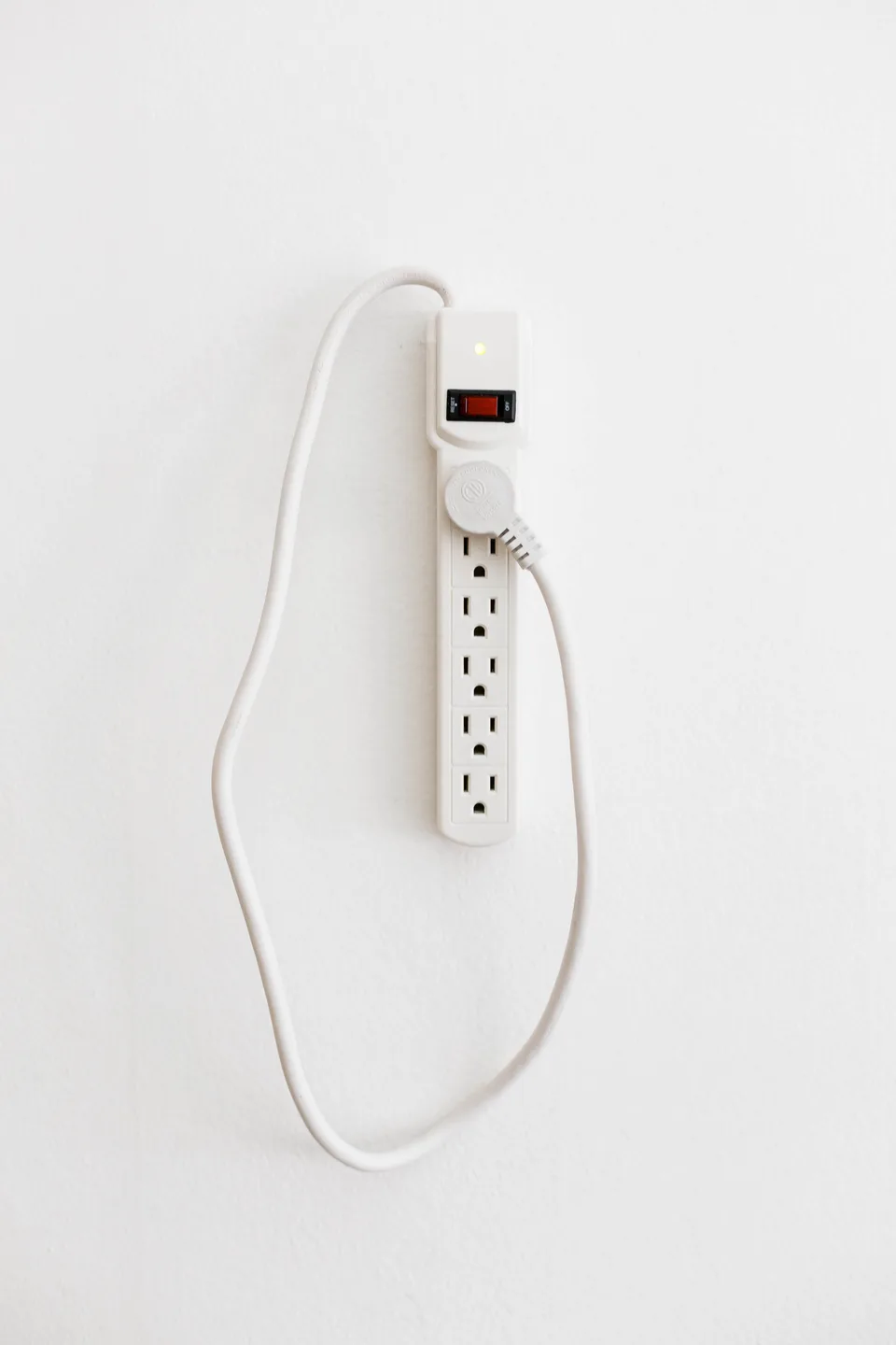 A white power strip with its own plug inserted into one of its outlets