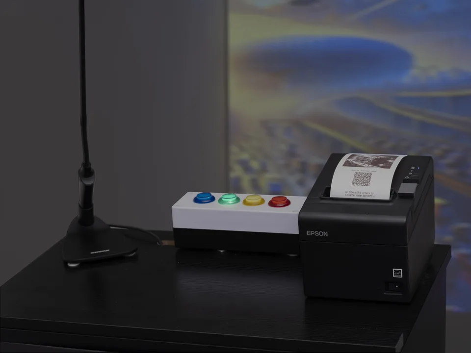 Four colored push buttons sit beside a receipt printer on a black podium in front of projected imagery.