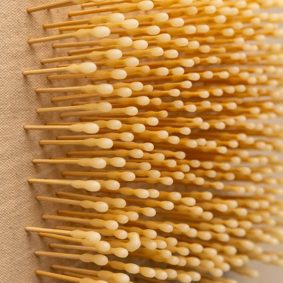 Angled close-up of the yellow-headed pins extending from the canvas.