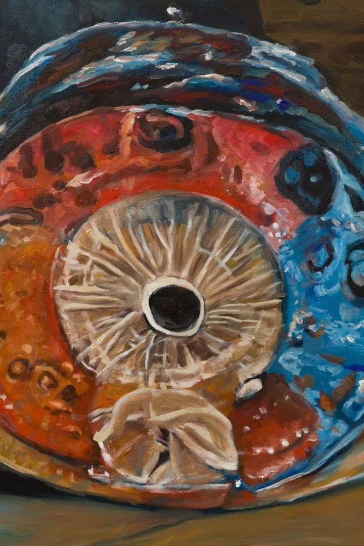 Detail of a painted blue and orange object with concentric, spoke-like forms around a dark opening.