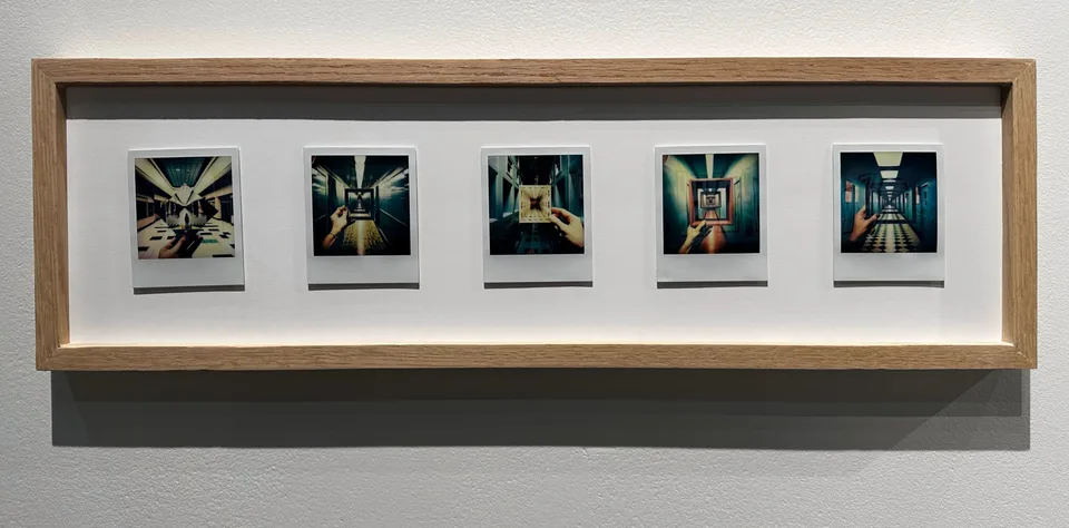Five Polaroids in a long wooden frame show hands holding nested rectangular pictures within corridors and patterned interiors.