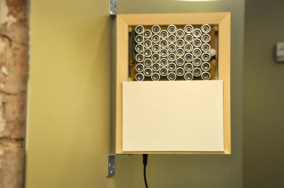 A rectangular array of small audio transducers mounted in a wooden box