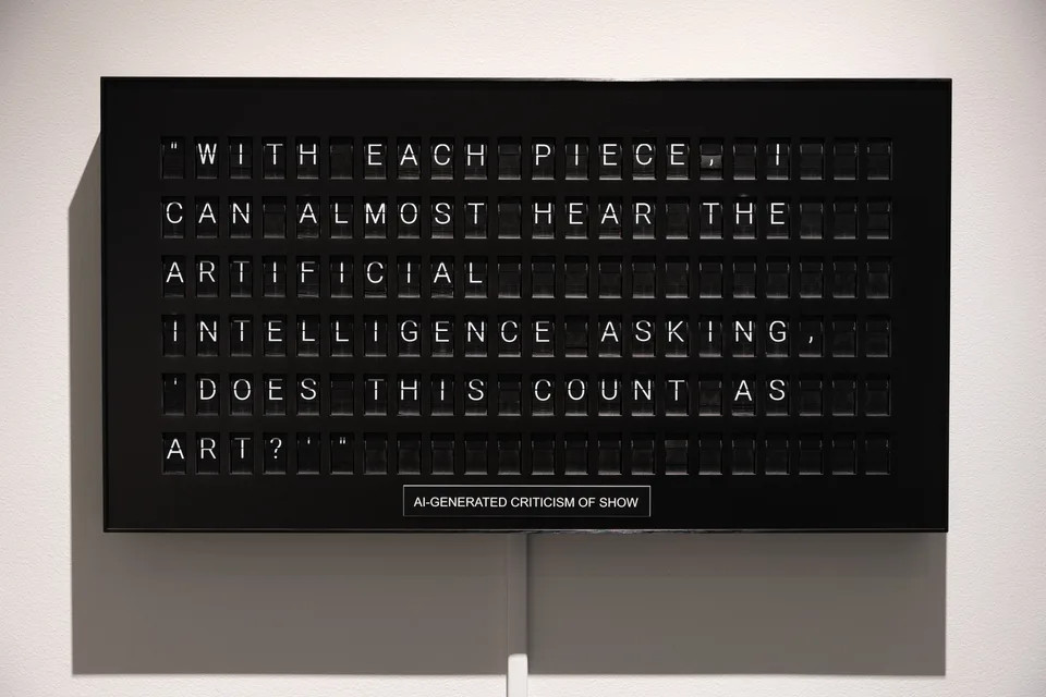 The split-flap board displays a generated criticism asking whether the work counts as art.