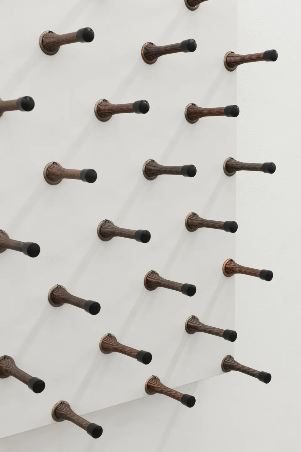 Detail of spring door stops projecting from a white panel