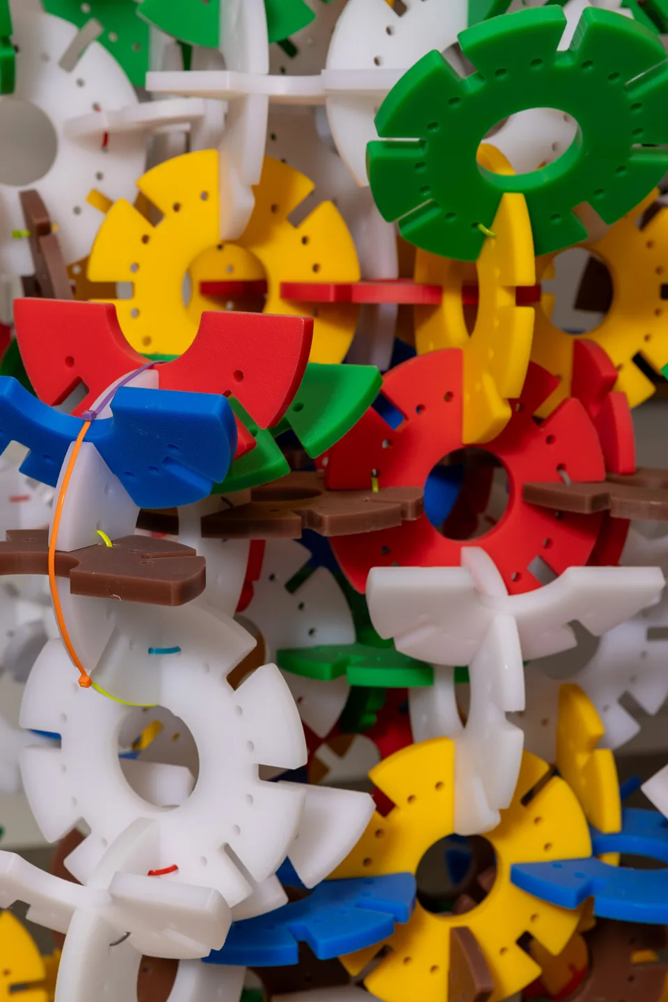 A close detail of interlocking yellow, blue, green, white and red forms in the tall sculpture.