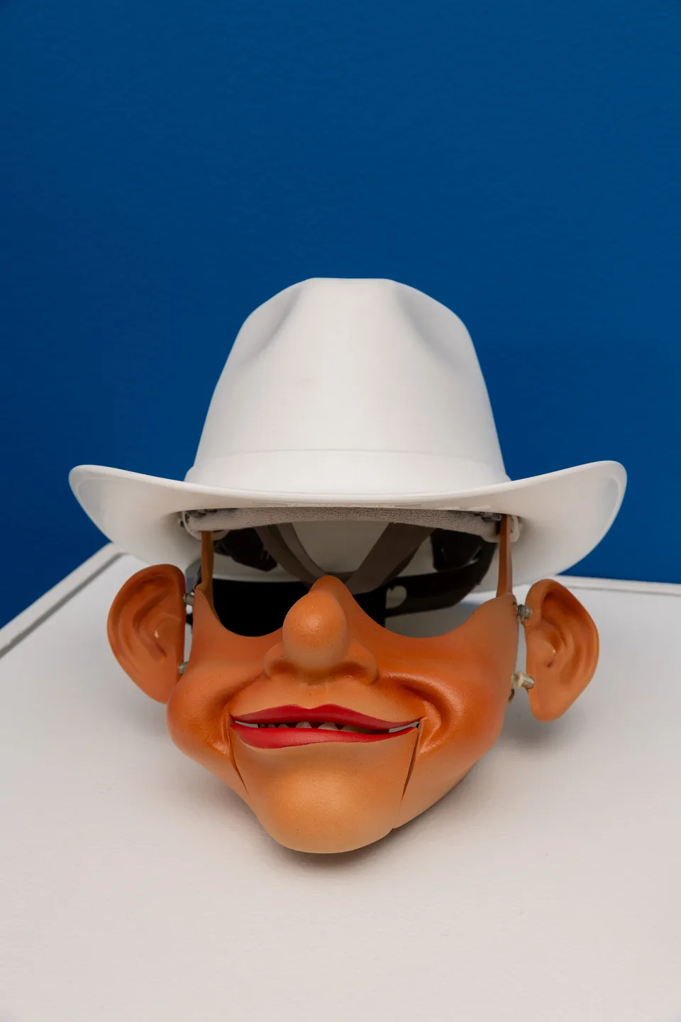 Close-up of the robotic character head wearing mirrored sunglasses and a white cowboy hat.