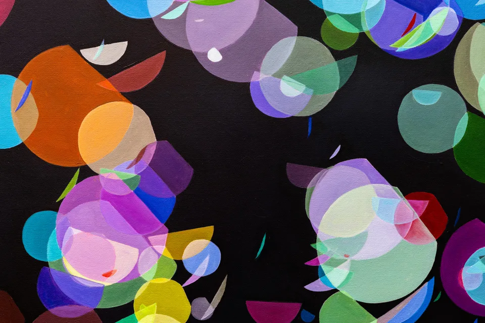Close-up of overlapping colorful circles painted on a black ground.