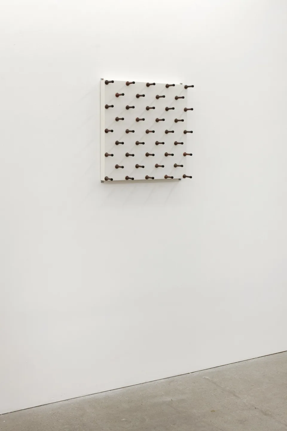 A panel of spring door stops installed on a gallery wall
