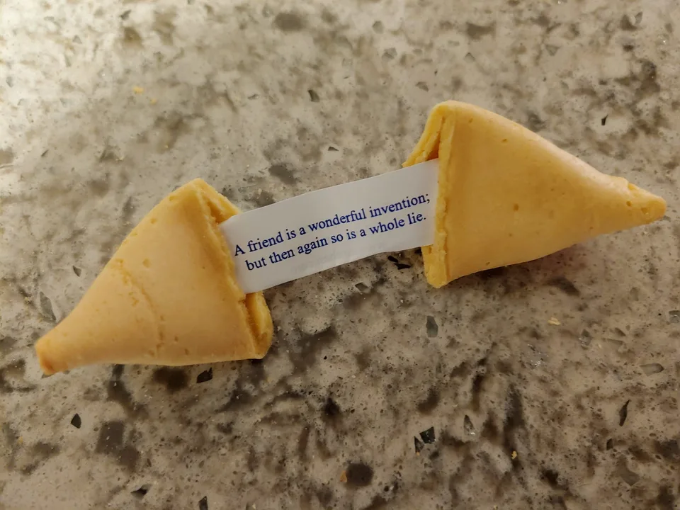 An opened fortune cookie holding a slip printed with an A.I. misfortunes message