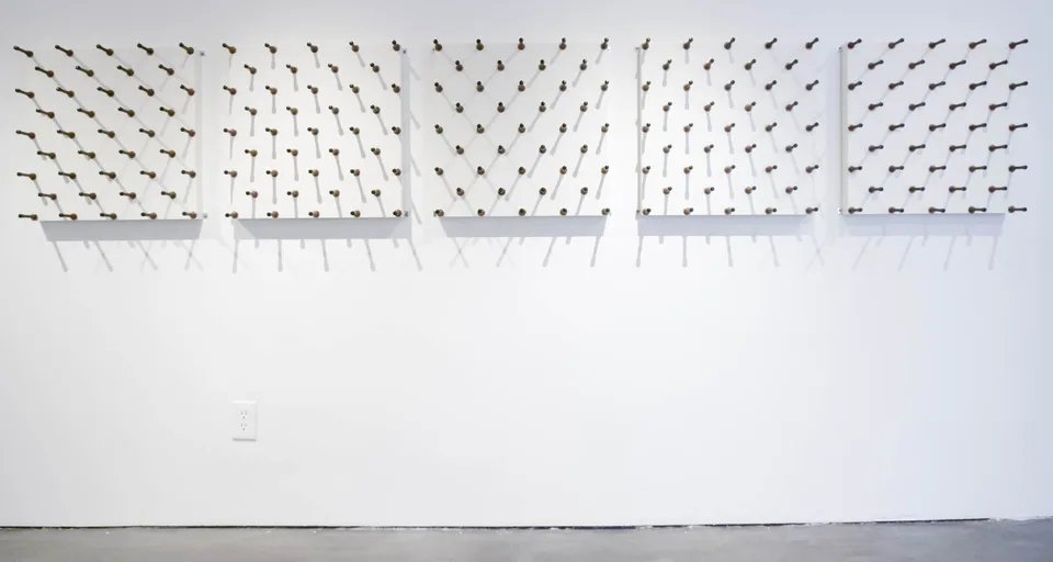Three wall-mounted panels covered in rows of spring door stops