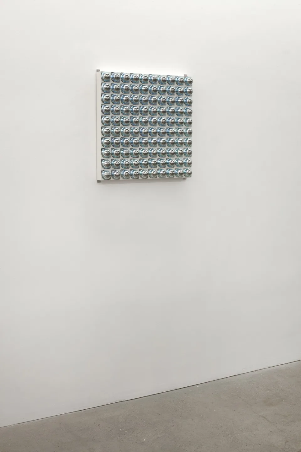 A grid of circular metal fittings installed on a white wall