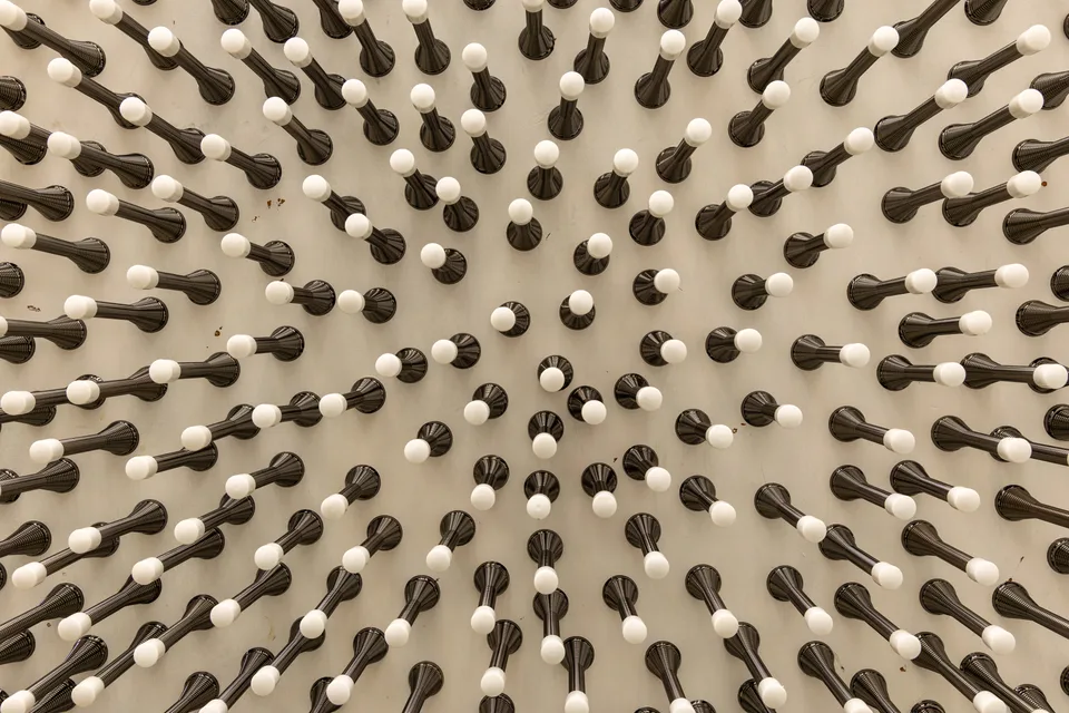 An angled detail shows a dense field of spring doorstops on the white door.
