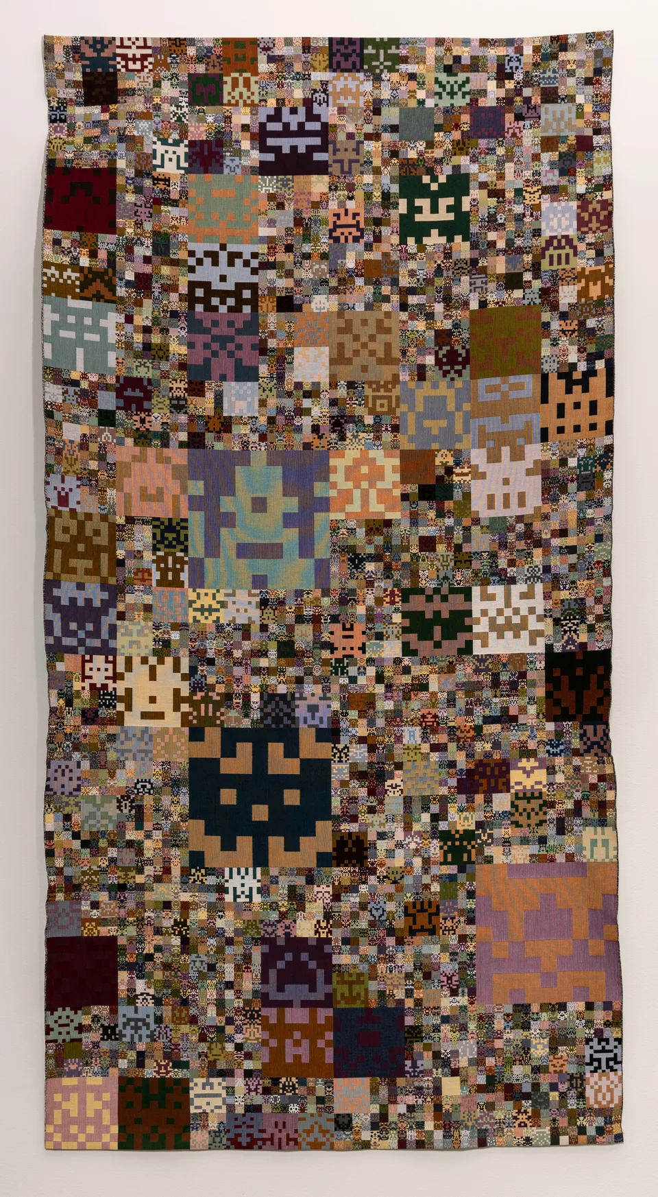 A tall woven textile filled with nested pixel-like geometric motifs.