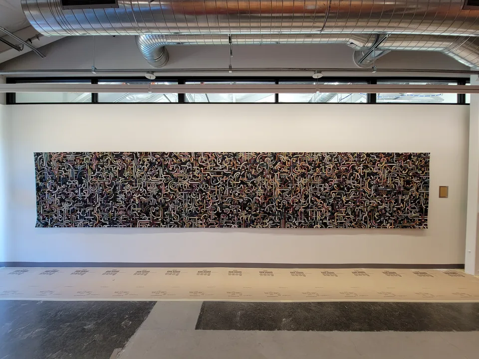 A large tapestry with intricate generated patterns hanging on a wall