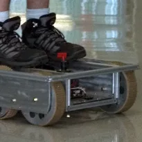 A boot standing on the metal chassis of Robot Rescue Platform above its large wheels
