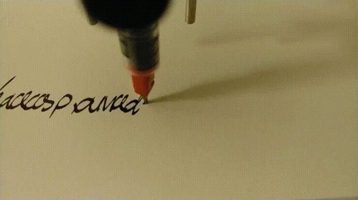 A robot-held pen draws flowing black handwriting on paper.