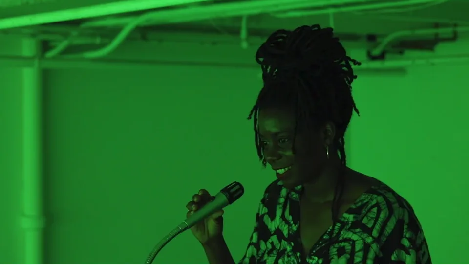 A visitor speaks into a microphone in a gallery illuminated with green light