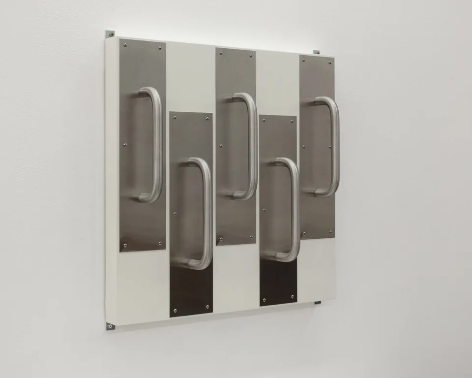 Angled view of metal door handles and their mounting plates