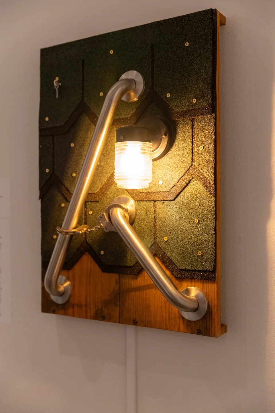 The roof-shingle and grab-bar assemblage seen at an angle with its lamp illuminated.