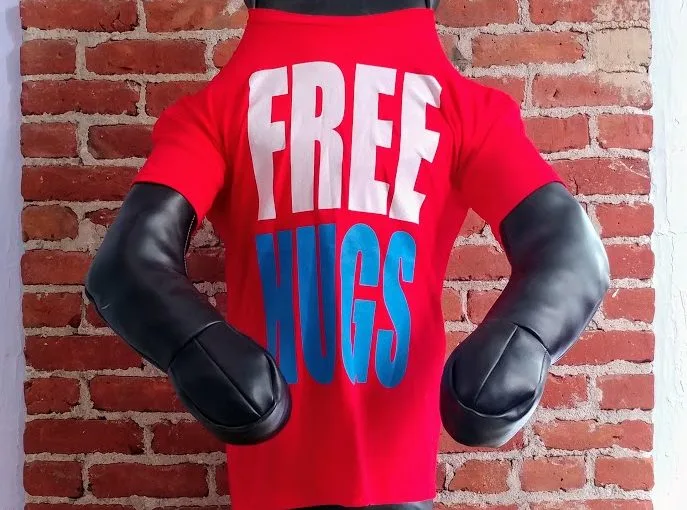 The padded torso and arms of a grappling dummy wearing a red Free Hugs T-shirt