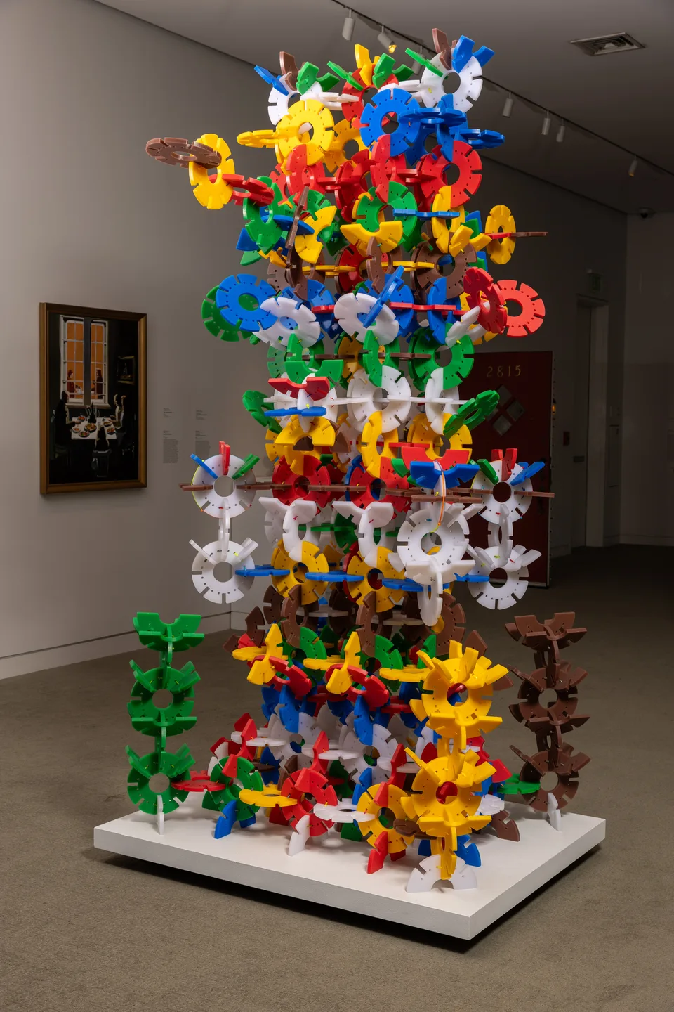 A tall freestanding tower of brightly colored interlocking forms stands on a white platform.