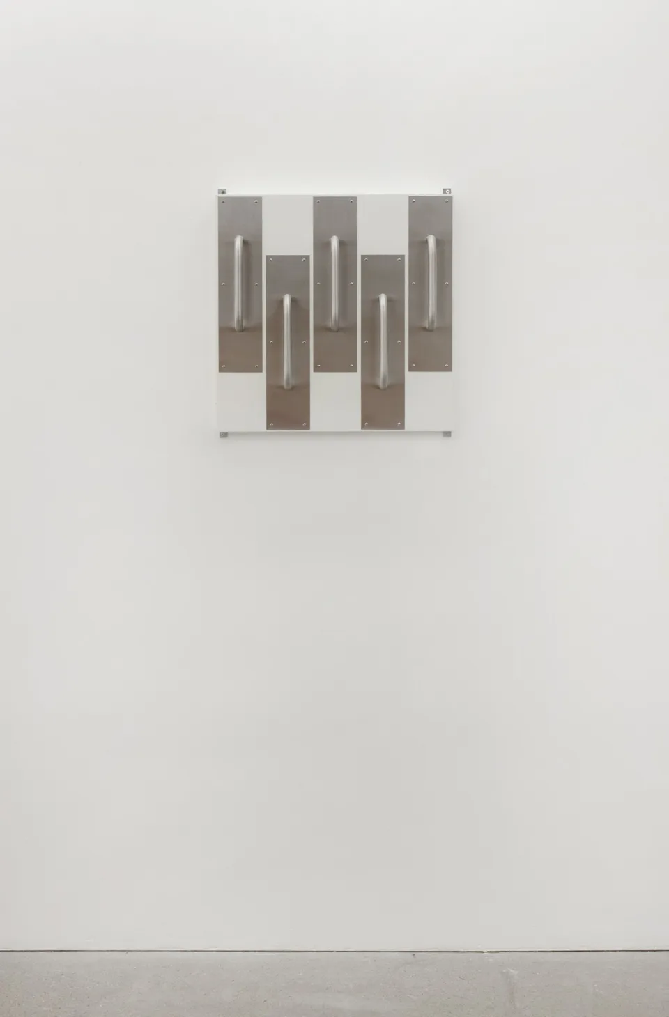 Front view of metal door handles mounted on a white panel