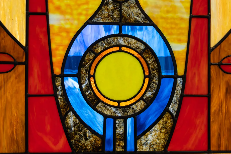 Detail of a circular yellow center surrounded by blue, red, and amber stained glass.