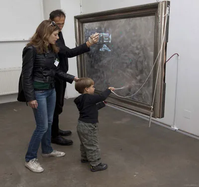Adults and a child explore a large framed sensor-data interface